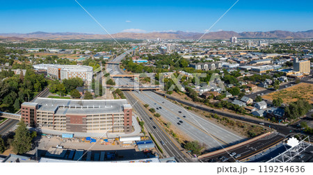 Aerial view of Reno, Nevada, featuring urban landscape, highways, and Sierra Nevada mountains under clear skies and bright daylight. 119254636