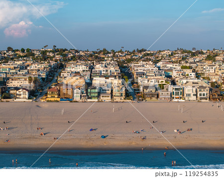 Scenic aerial view of Manhattan Beach, Los Angeles, showing sandy beach, beachgoers, volleyball courts, Pacific Ocean waves, and residential homes. 119254835