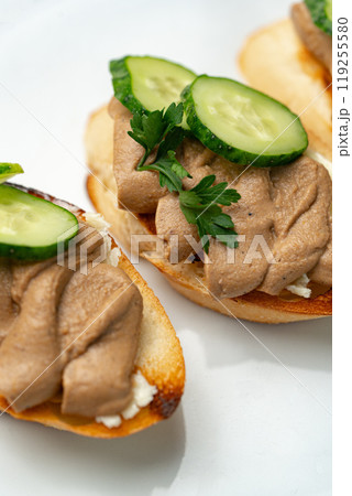 Savory canapes topped with creamy spread and cucumber slices served on toasted bread at a casual gathering 119255580