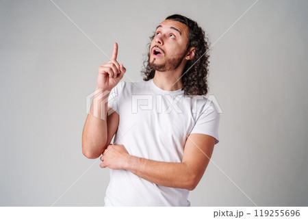 Young man with curly hair gestures upward while expressing a thoughtful idea Young man with curly hair gestures upward while expressing a thoughtful idea 119255696