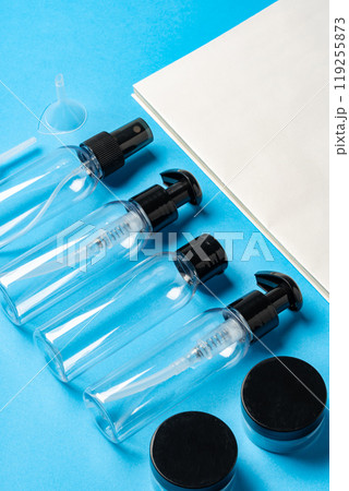 Various clear plastic bottles and containers arranged on a blue background 119255873
