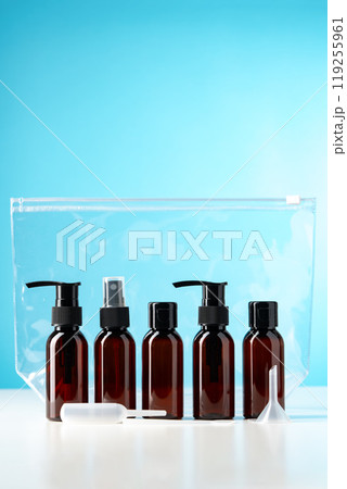 Collection of amber glass bottles with pumps and spray tops on a light blue background 119255961