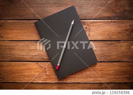 Closed notebook and pencil on a rustic wooden board Closed notebook and pencil on a rustic wooden board 119258398