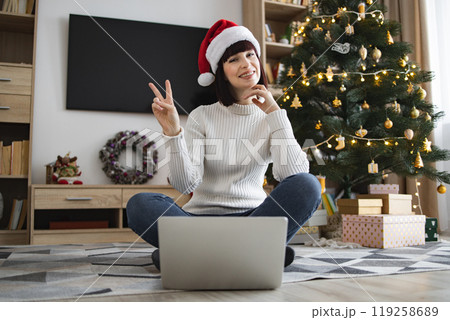 Young woman with Santa hat celebrating Christmas at home Young woman with Santa hat celebrating Christmas at home 119258689