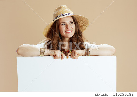 smiling elegant woman showing blank board isolated on beige 119259188
