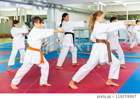 Female trainer is training teenagers in karate class Female trainer is training teenagers in karate class 119259867