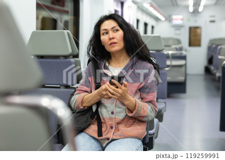 Woman passenger using phone in intercity train 119259991