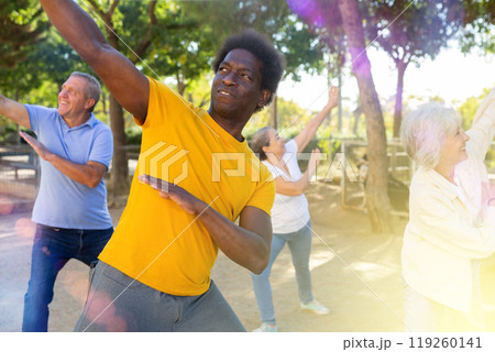 Positive multiracial mature casual pensioners practicing group dancing outdoors in autumn 119260141