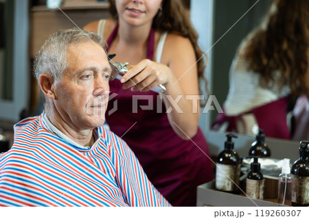 Hairdresser cutting hair of male client. Hairstylist serving client at barber shop Hairdresser cutting hair of male client. Hairstylist serving client at barber shop 119260307