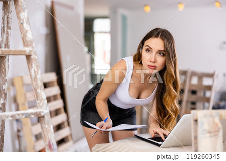 Woman designer using laptop in construction site 119260345
