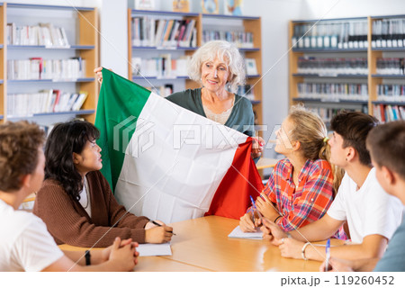 Mature female teacher shows scholchildren the national flag of Italy 119260452