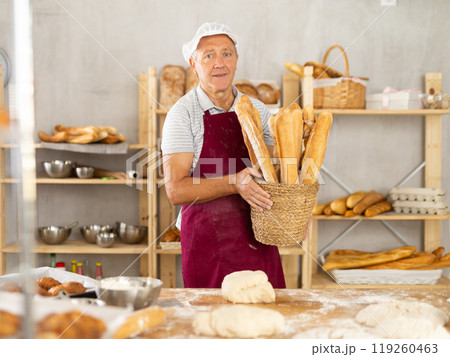 Elderly man baker with basket of baguettes 119260463