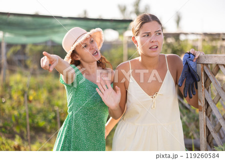 Adult and young woman quarreling in garden Adult and young woman quarreling in garden 119260584