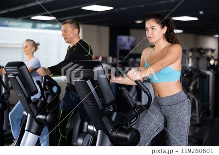 Young girl doing cardio training on elliptical trainer in gym Young girl doing cardio training on elliptical trainer in gym 119260601