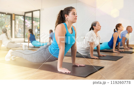 Group of young mature old people in sportswear exercising Pilates while stretching on mats in rehabilitation center 119260778