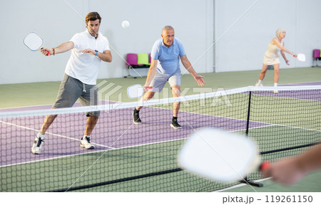 Adult man playing doubles pickleball in team with older partner 119261150