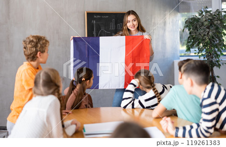 Geography lesson in school class - teacher talks about France, holding flag in his hands Geography lesson in school class - teacher talks about France, holding flag in his hands 119261383