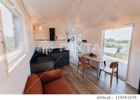Modern open-concept kitchen and living area with natural light, cozy seating, and warm wooden design 119261876