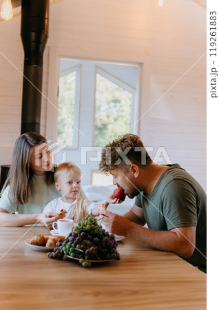 Father and son enjoying breakfast together with fresh fruit and pastries, creating family moment 119261883