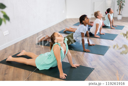 In sport studio with group of friends girl stand perform dog muzzle up, Urdhva Mukha Shvanasana In sport studio with group of friends girl stand perform dog muzzle up, Urdhva Mukha Shvanasana 119261916