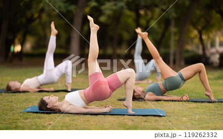 Group of young women doing yoga in park 119262332