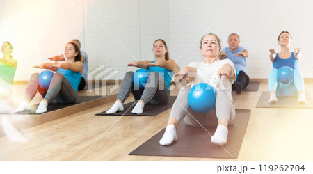 Elderly woman doing sit-ups with pilates bender ball 119262704