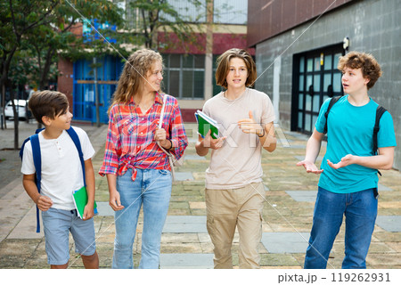Four teenagers talking about play on walk in street 119262931