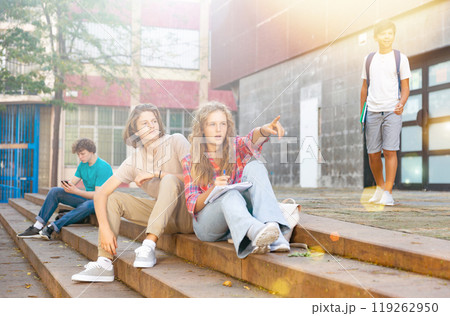 Teenagers sitting on stairs beside school 119262950
