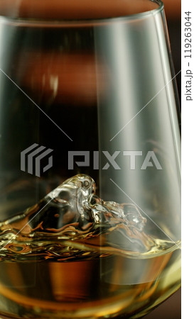 Close-up of white wine pouring into glass , freeze motion. 119263044