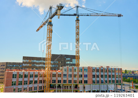 Two large tower cranes at construction site against clear blue sky. Modern building under development. Scandinavian architecture under construction 119263401
