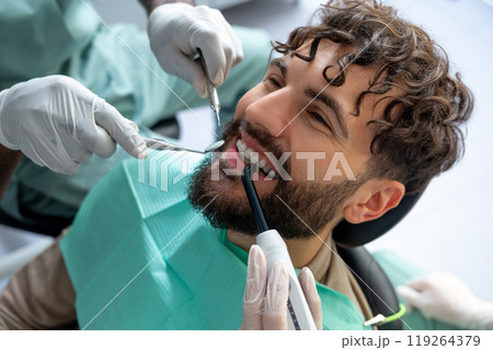 Dentist doing oral examination on patient with equipment to promote safety and hygiene Dentist doing oral examination on patient with equipment to promote safety and hygiene 119264379