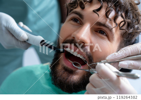 Dentist doing oral examination on patient with equipment to promote safety and hygiene Dentist doing oral examination on patient with equipment to promote safety and hygiene 119264382