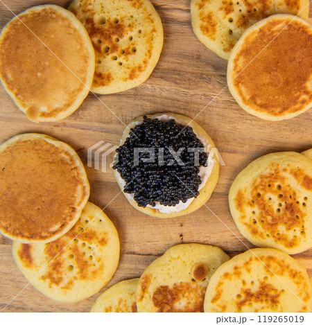 Blinis with black caviar and cream cheese, on a festive dish, mini pancakes, an elegant appetizer Blinis with black caviar and cream cheese, on a festive dish, mini pancakes, an elegant appetizer 119265019
