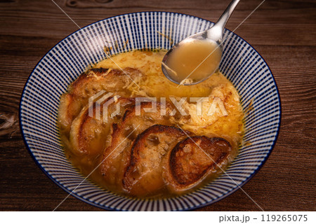 Classic French onion soup baked with cheese croutons sprinkled with fresh thyme, close up view. 119265075