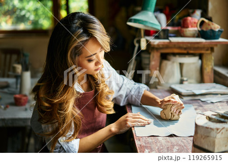 Female potter sculpts from clay at her workshop. Female potter sculpts from clay at her workshop. 119265915
