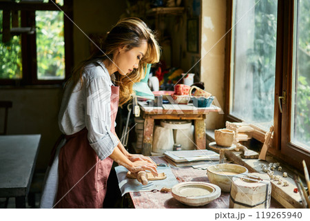 Female potter sculpts from clay at her workshop. Female potter sculpts from clay at her workshop. 119265940
