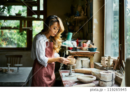 Female artist sculpts crafts with ceramic clay at her creative workshop Female artist sculpts crafts with ceramic clay at her creative workshop 119265945