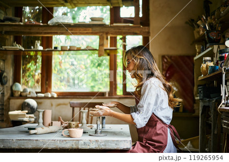 Female artist sculpts crafts with ceramic clay at her creative workshop Female artist sculpts crafts with ceramic clay at her creative workshop 119265954