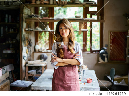 Successful female artist posing at creative workshop with her artwork in the background 119265959