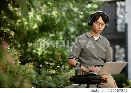 Medium shot of Asian male IT developer concentrated on using laptop to write code 119267291