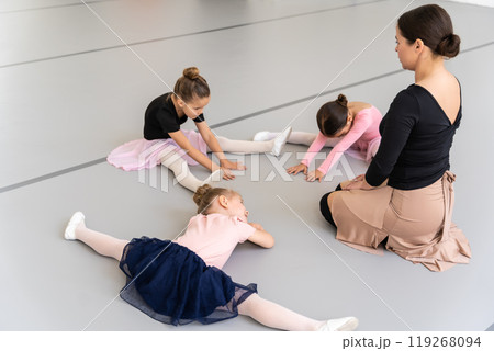Pretty girls sitting on floor in ballet studio practicing stretching during classical dance training 119268094