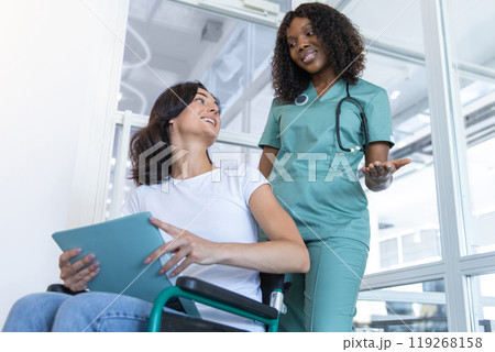 African american female doctor with a patient in a wheelchair in the clinic corridor African american female doctor with a patient in a wheelchair in the clinic corridor 119268158