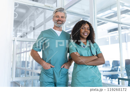 Two doctors looking contented and confident while standing in the hospital corridor Two doctors looking contented and confident while standing in the hospital corridor 119268172