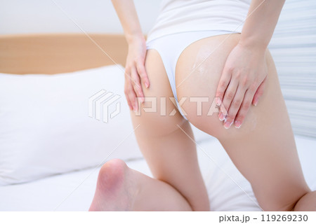 ベッドでボディクリームをお尻に塗る下着姿の若いスレンダーな女性　スキンケア　ボディケア　ヒップケア 119269230