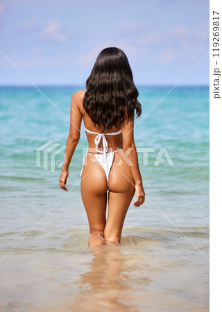 Beautiful asian girl in white bikini posing at the tropical beach, back view 119269817