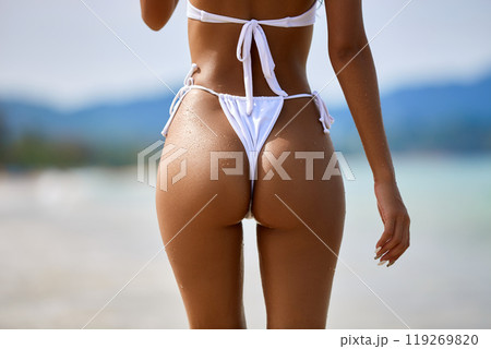 Beautiful asian girl in white bikini posing at the tropical beach, back view 119269820
