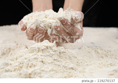 Baker working with white wheat flour, hands close-up. 119270137