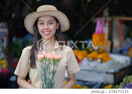 A woman wearing a straw hat and holding a bouquet of flowers 119271235