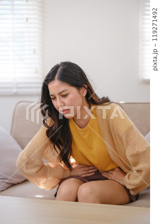 A woman in a yellow shirt is sitting on a couch with her back to the camera 119271492