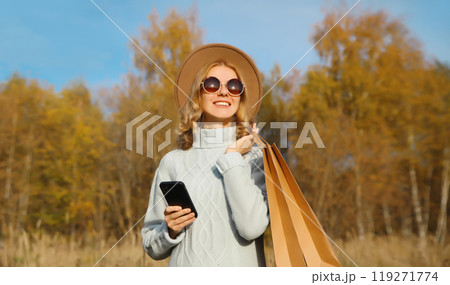 Stylish happy young woman with shopping bag, smartphone in autumn park, girl smiling using phone Stylish happy young woman with shopping bag, smartphone in autumn park, girl smiling using phone 119271774